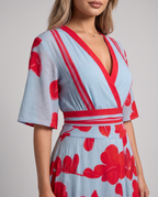 Close-up of the red-trimmed V-neckline, flared sleeves and striped waistband of the floral maxi dress