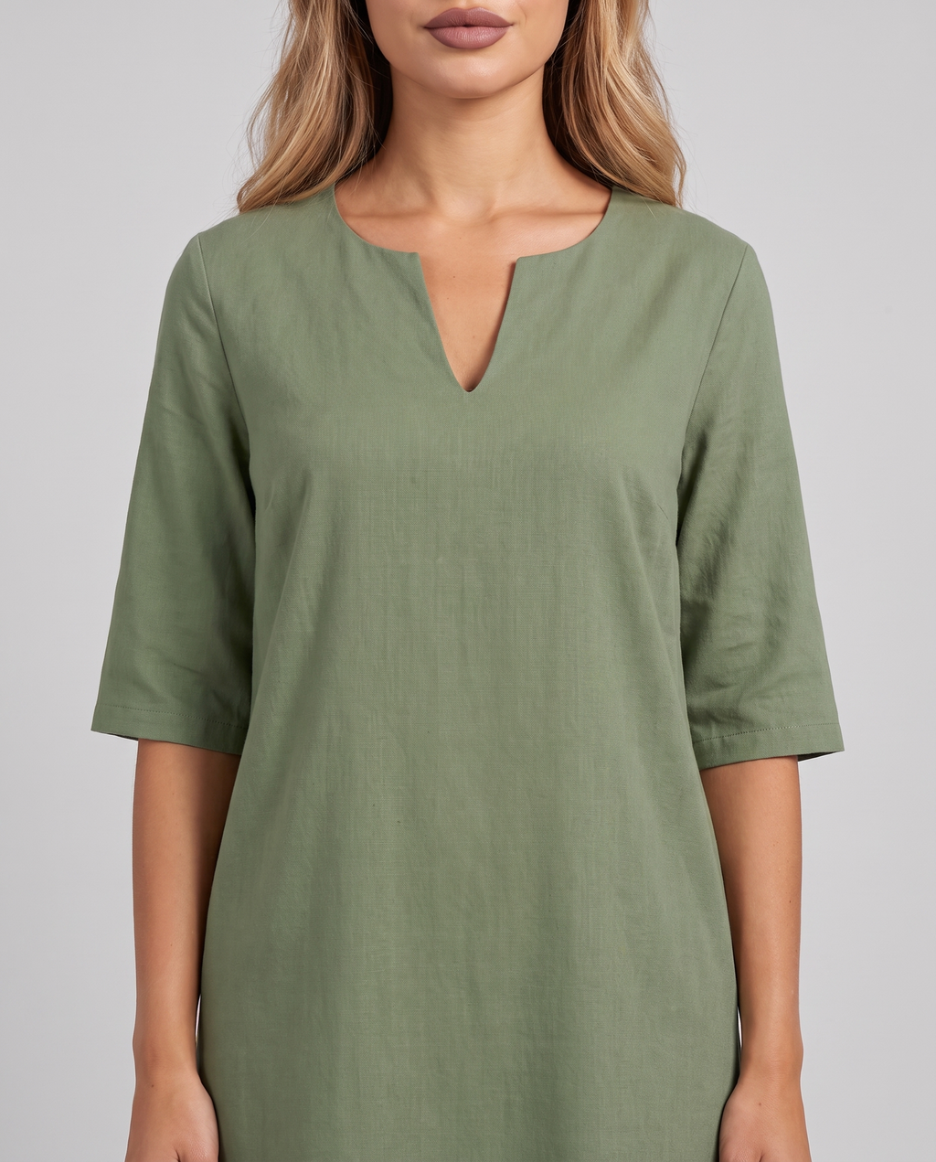 Close-up of the notched V-neckline and elbow sleeves of the green shift dress
